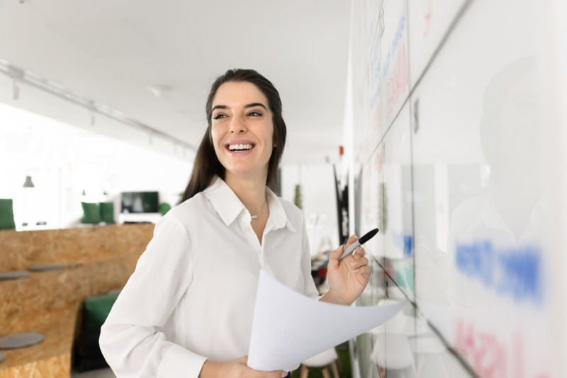 An educational leader presenting to a team using a white board