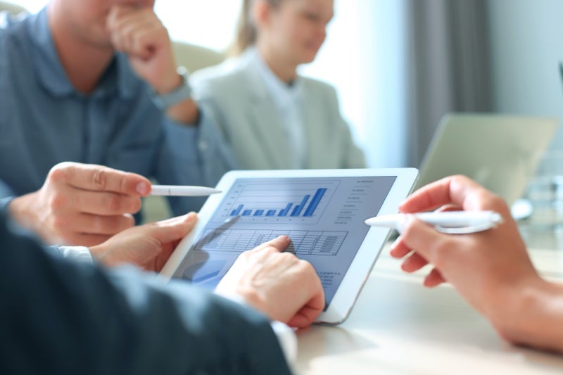 Groupof business analysts analyzing data on a tablet device