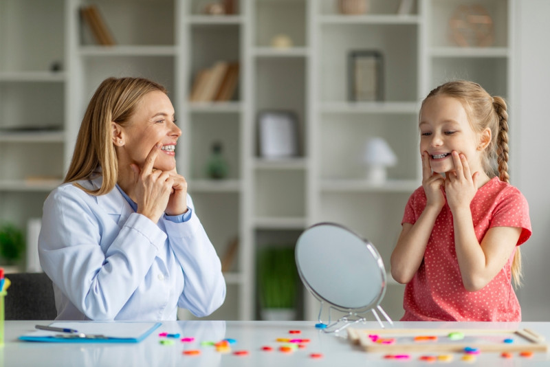 A female SLP helping a young client form proper mouth sounds